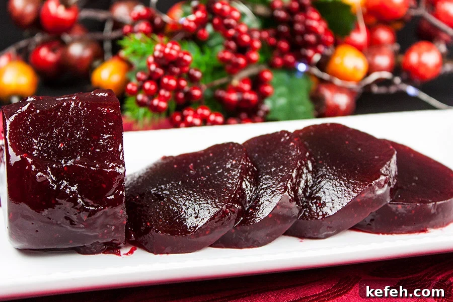 Homemade Cranberry Sauce: Jellied or Whole-Berry Recipe 9 Cranberry sauce sliced on a white tray with berries in the background.