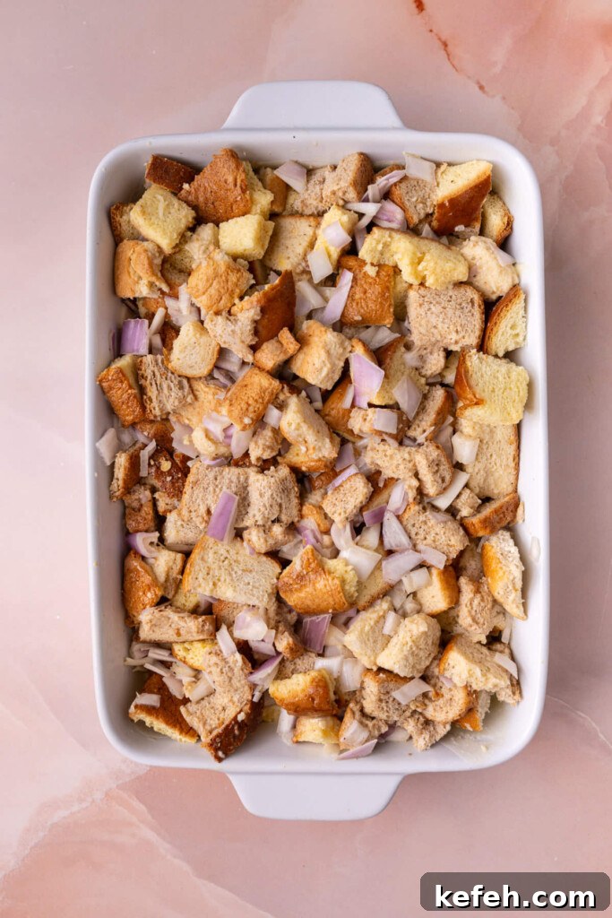 Savory Chive French Toast Casserole Recipe for Brunch 7 Casserole dish layered with butter, bread, and a seasoned egg wash with shallots.
