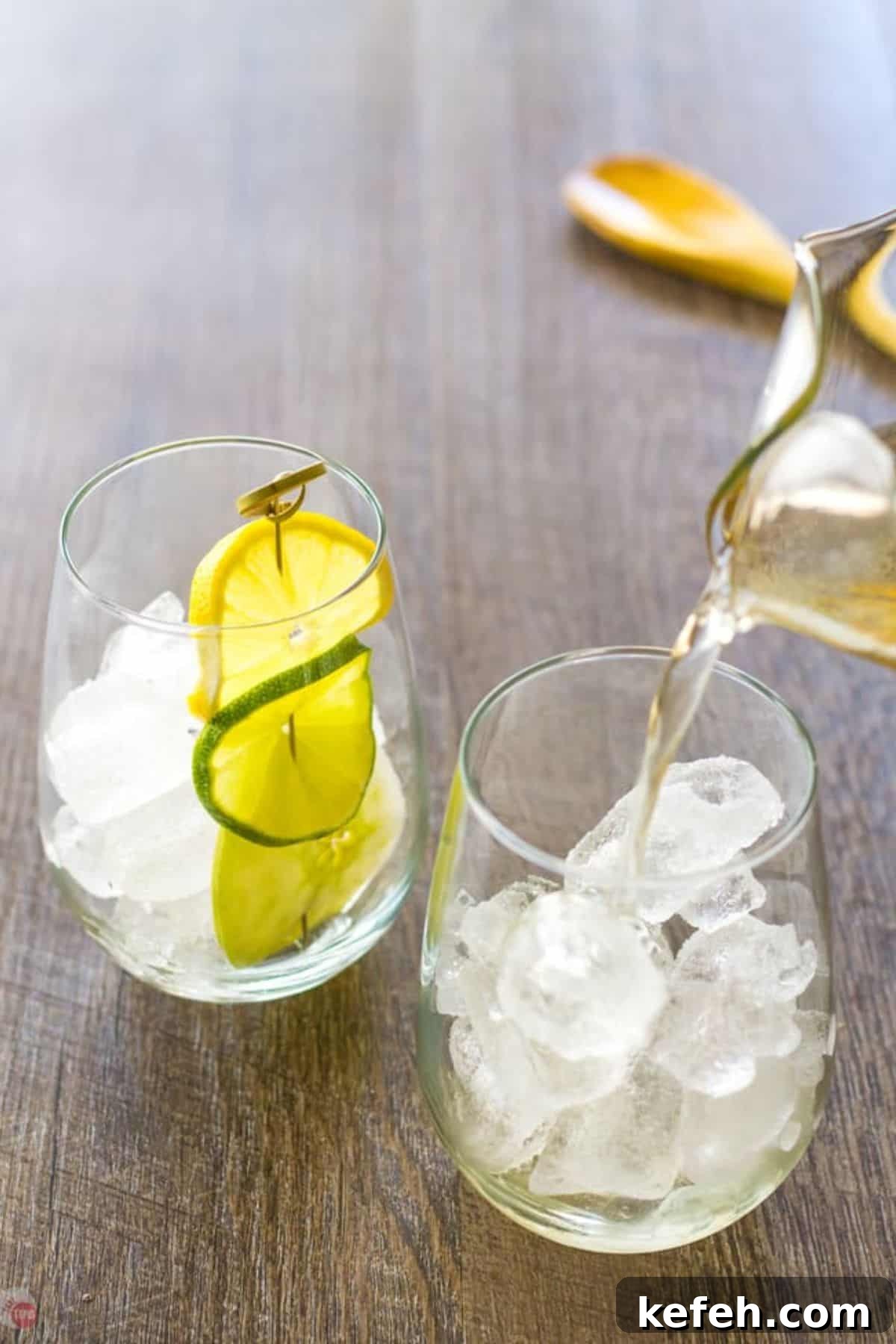 Refreshing Summer Sangria Recipe with Fresh Fruit 5 pitcher pouring sangria into a wine glass with ice cubes and lime slices in it