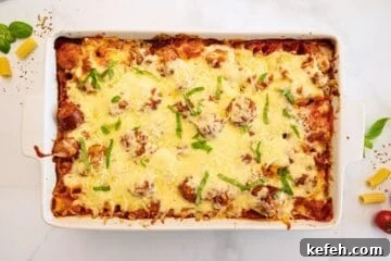 Cheesy Baked Rigatoni with Marinara and Mozzarella 7 Baked Rigatoni in white casserole dish with melty layer of mozzarella cheese and ribbons of fresh basil.