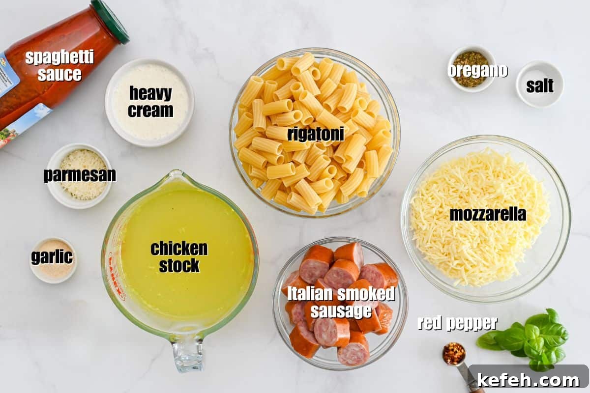 Creamy Cheesy Baked Rigatoni Ingredients for pasta bake labeled on counter showing uncooked rigatoni, smoked Italian sausage, spaghetti sauce, heavy creamy, seasonings, broth, and cheese.