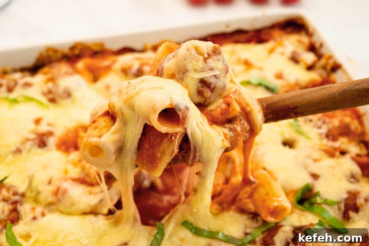 Cheesy Baked Rigatoni with Marinara and Mozzarella 2 Spoonful of tender rigatoni noodles covered in creamy red sauce and melted mozzarella coming from large baking dish.