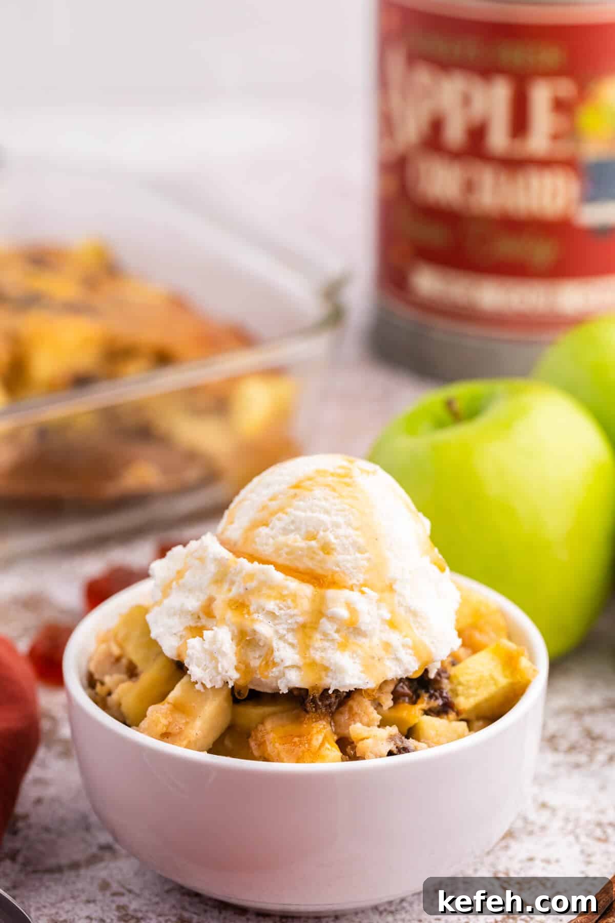 A bowl of maple apple pudding with vanilla ice cream and maple syrup on top.
