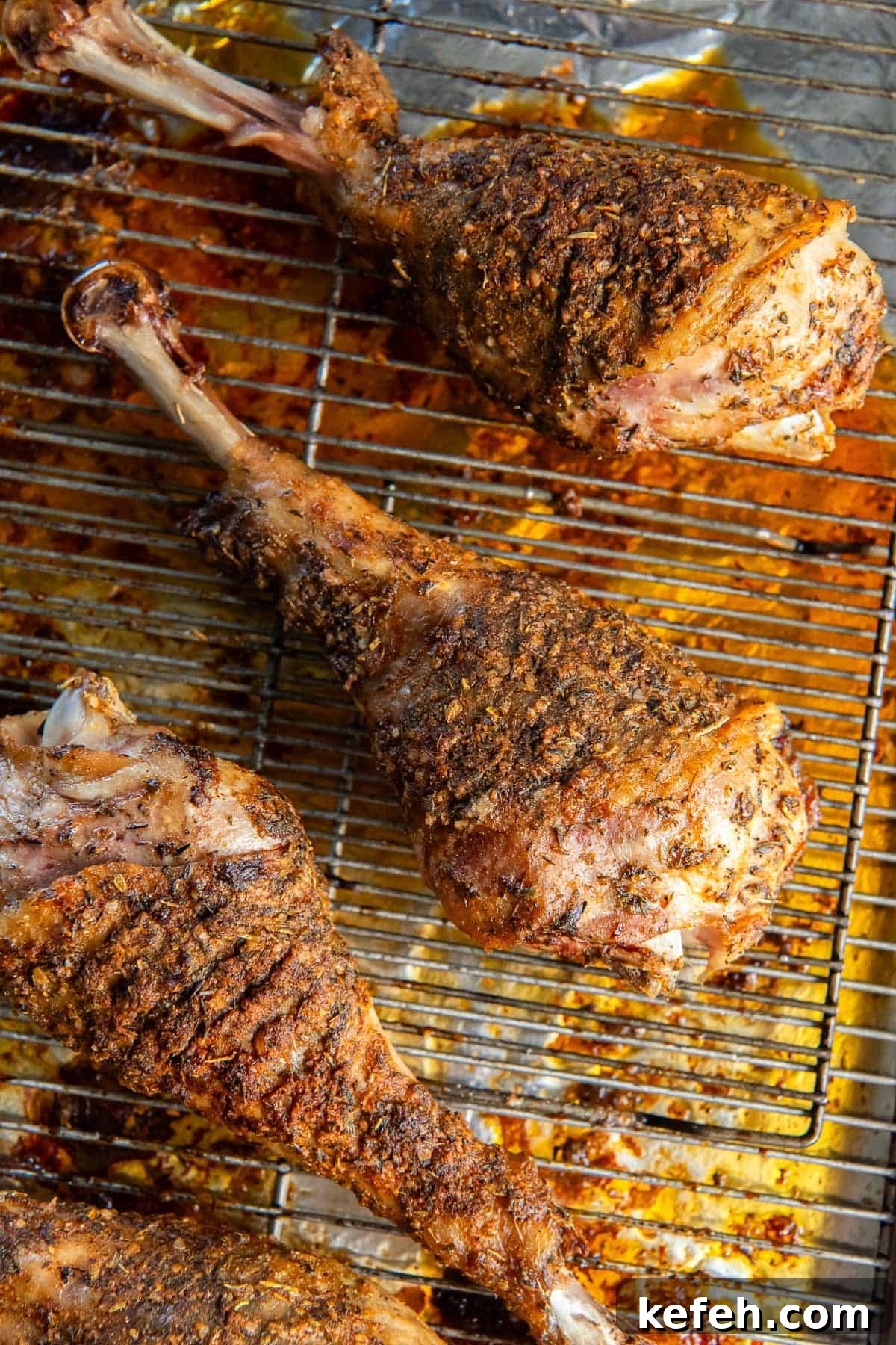 Roasted turkey drumsticks on a wire rack on a baking sheet.