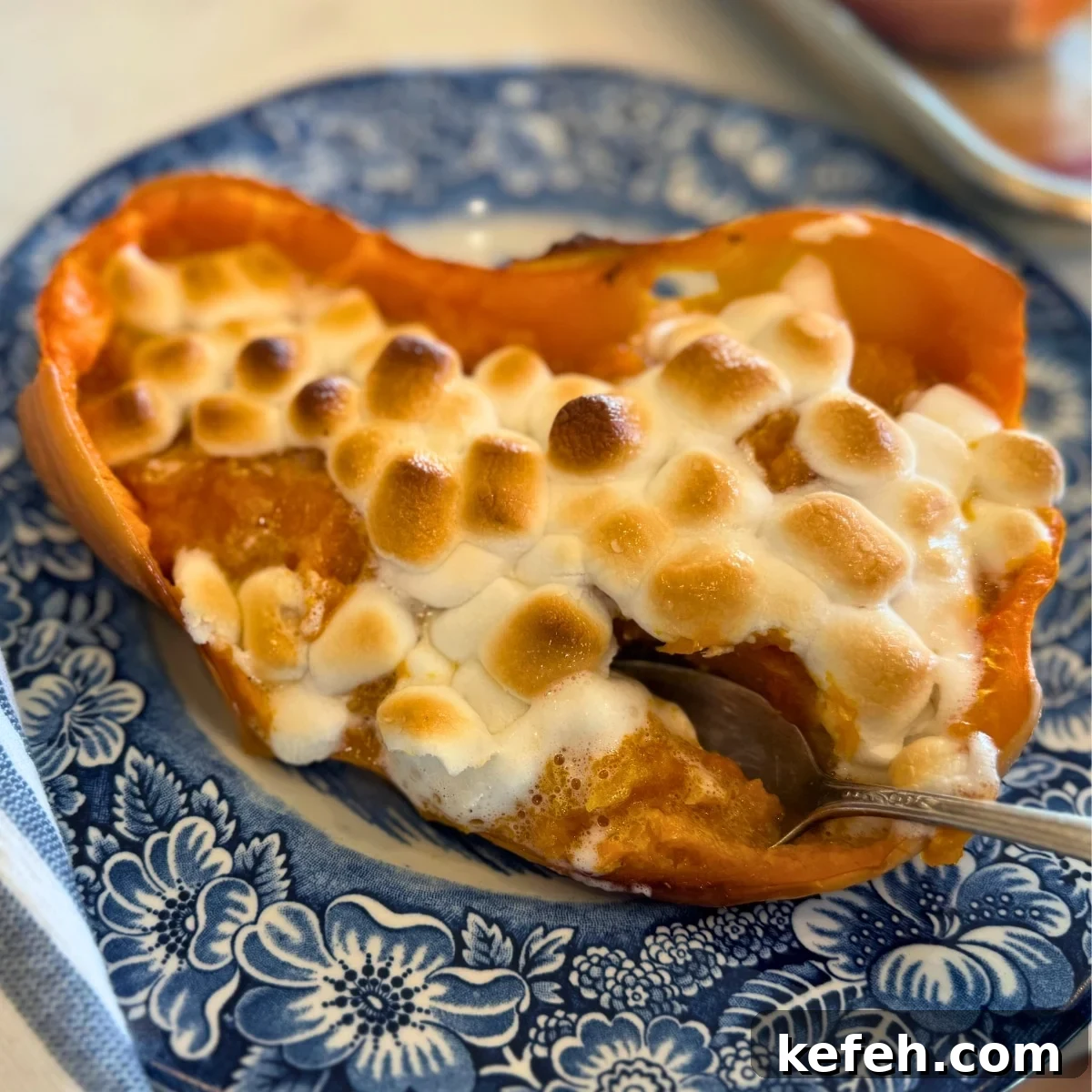 Twice-Baked Butternut Squash with Toasted Marshmallow Topping 5 twice baked butternut squash topped with toasted marshmallows on a blue plate with a spoon in it