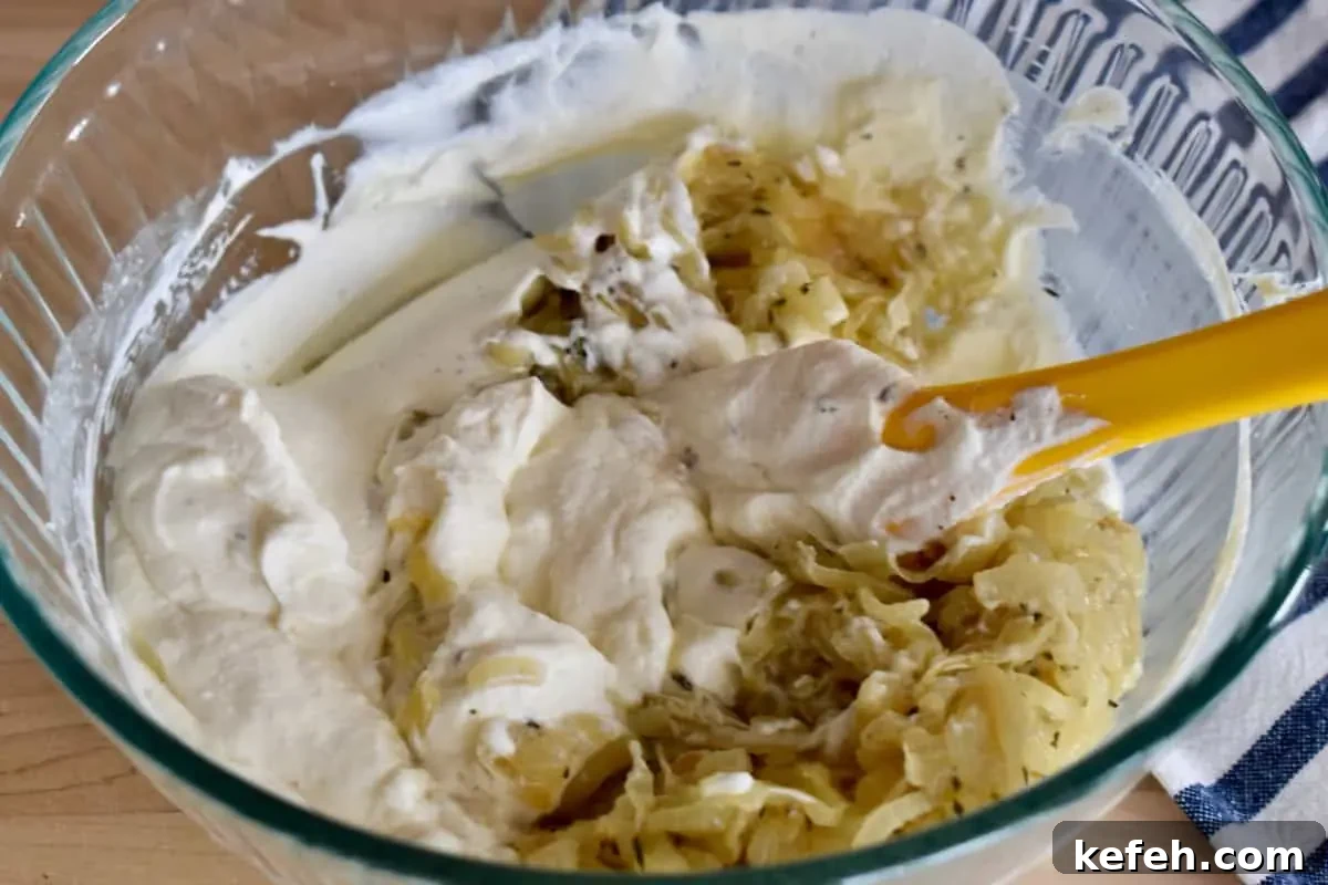 Caramelized Onion Dip Made with Greek Yogurt — Savory Party Dip 7 Ingredients in a glass bowl with a rubber spatula.