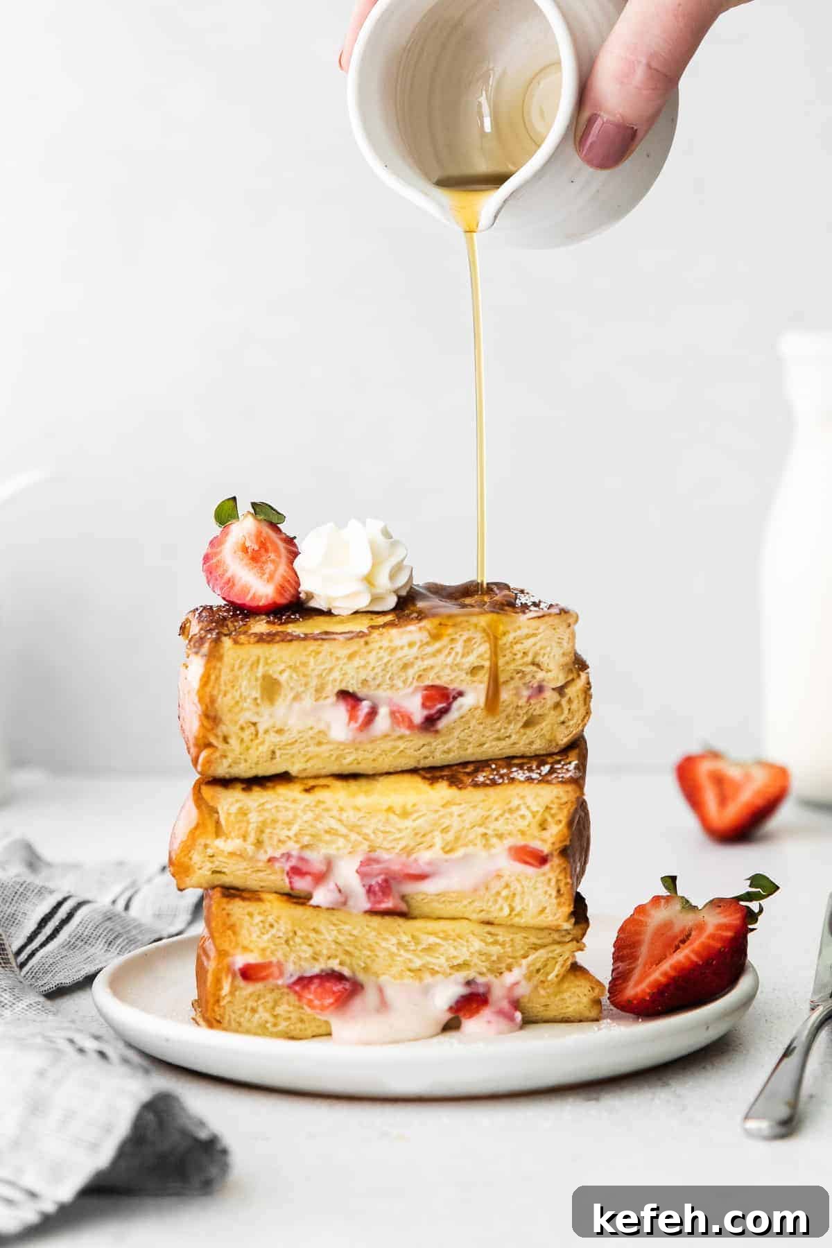 This deliciously decadent strawberries and cream stuffed French toast is perfect for your next brunch or special occasion. Stuffed french toast with maple syrup being poured over it.