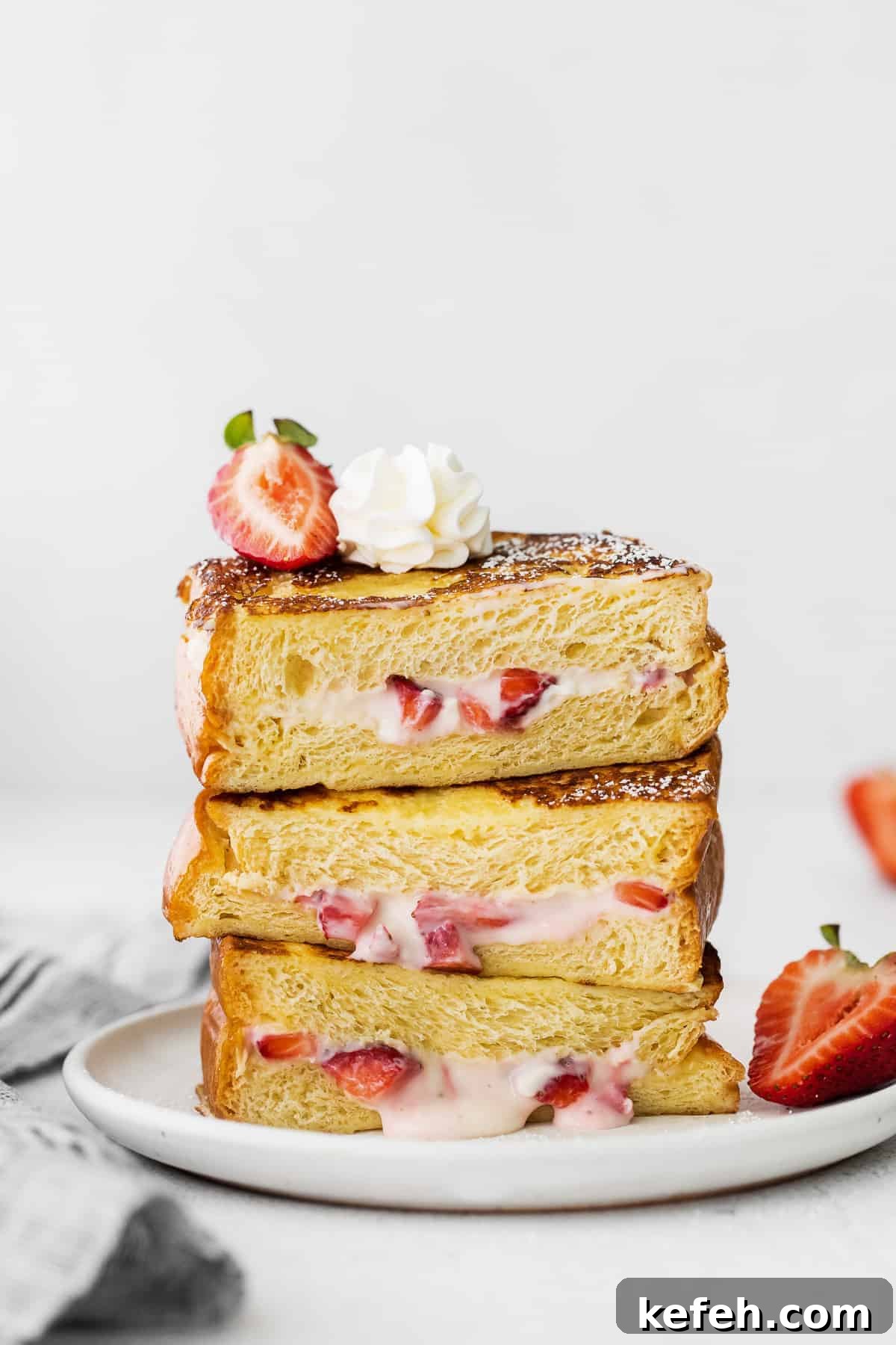 This deliciously decadent strawberries and cream stuffed French toast is perfect for your next brunch or special occasion. Strawberries and cream stuffed french toast stacked three slices high.