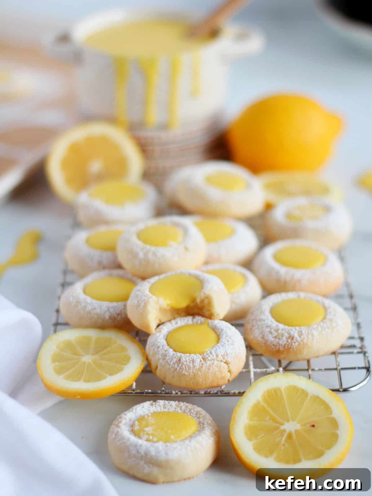 Lemon thumbprint cookies filled with homemade lemon curd. Placed on cooling rack with lemons in background.