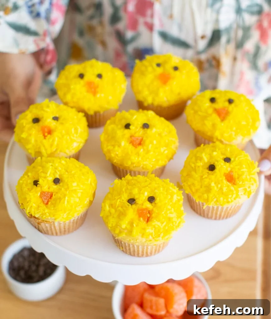 Yellow Easter chick cupcakes on a white cake stand.