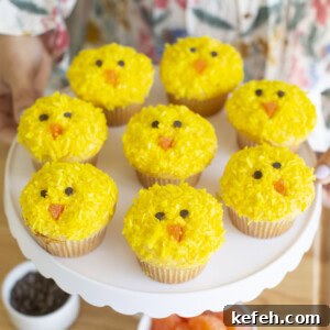 Yellow Easter chick cupcakes on a white cake stand.