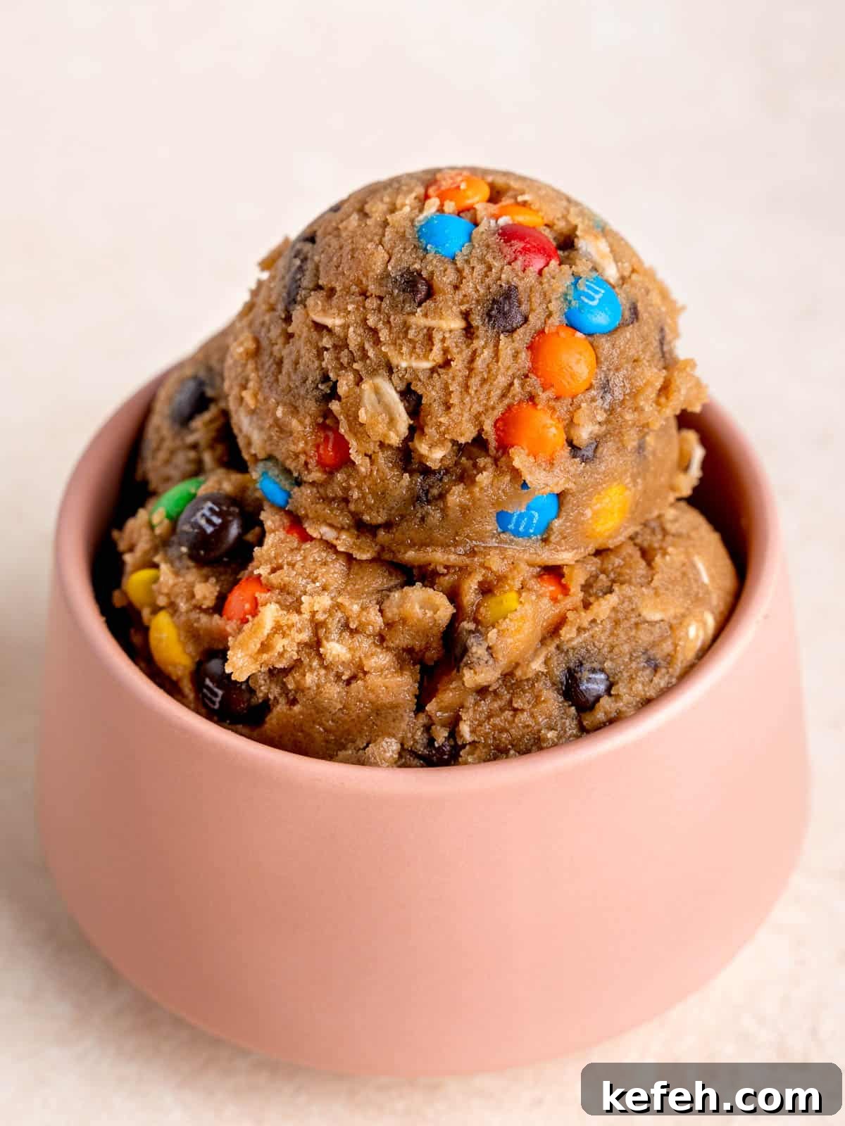 Edible Monster Cookie Dough Recipe for Safe No-Bake Treats 5 Scoops of edible cookie dough in a pink bowl.