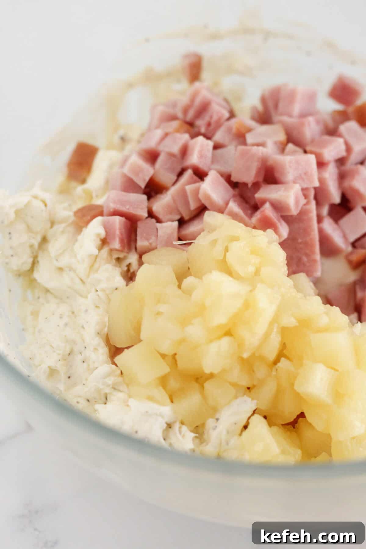 Adding the pineapple and ham to the dip.