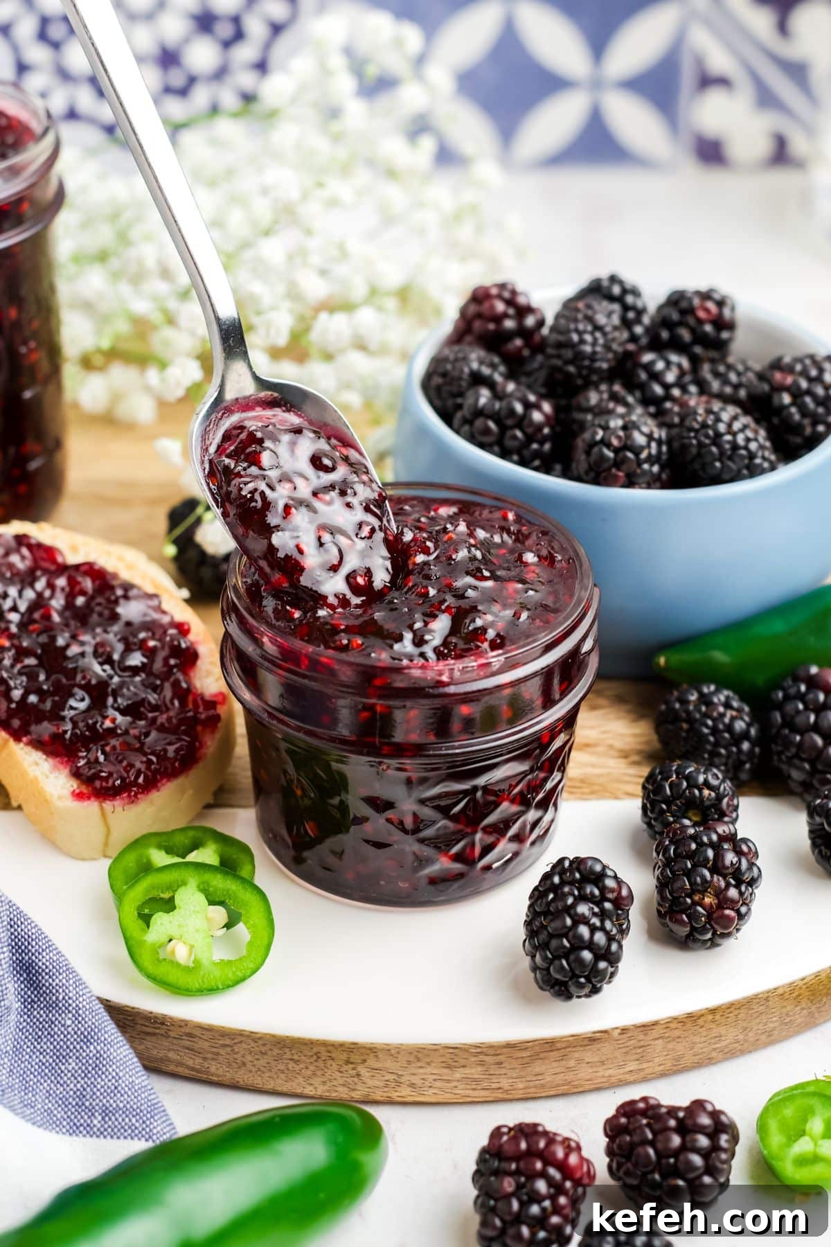 Spicy Blackberry Jalapeño Jam Recipe for Preserving and Gifts 2 A jar of blackberry jalapeno jam with a spoon holding a bit up over the jar.