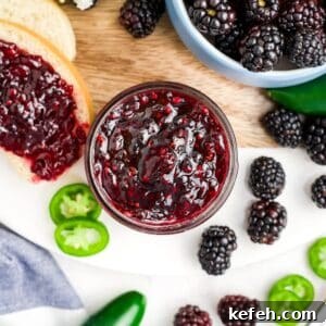 Spicy Blackberry Jalapeño Jam Recipe for Preserving and Gifts 14 Blackberry jalapeno jam in a jar surrounded by fresh berries and jalapeno slices.