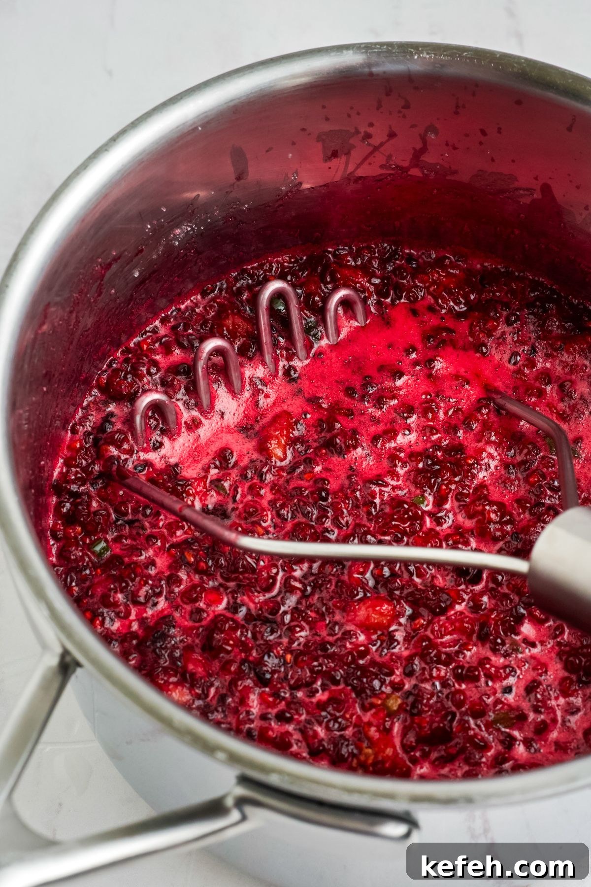 Spicy Blackberry Jalapeño Jam Recipe for Preserving and Gifts 6 Cooked blackberry jam in a pan with a masher.