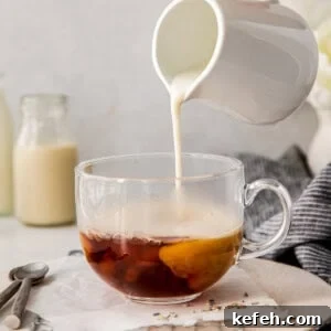 A person pouring milk into a cup of London Fog drink.