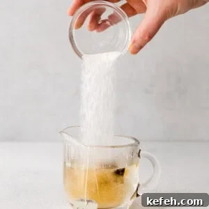 a hand is pouring sugar into a cup of London fog tea.