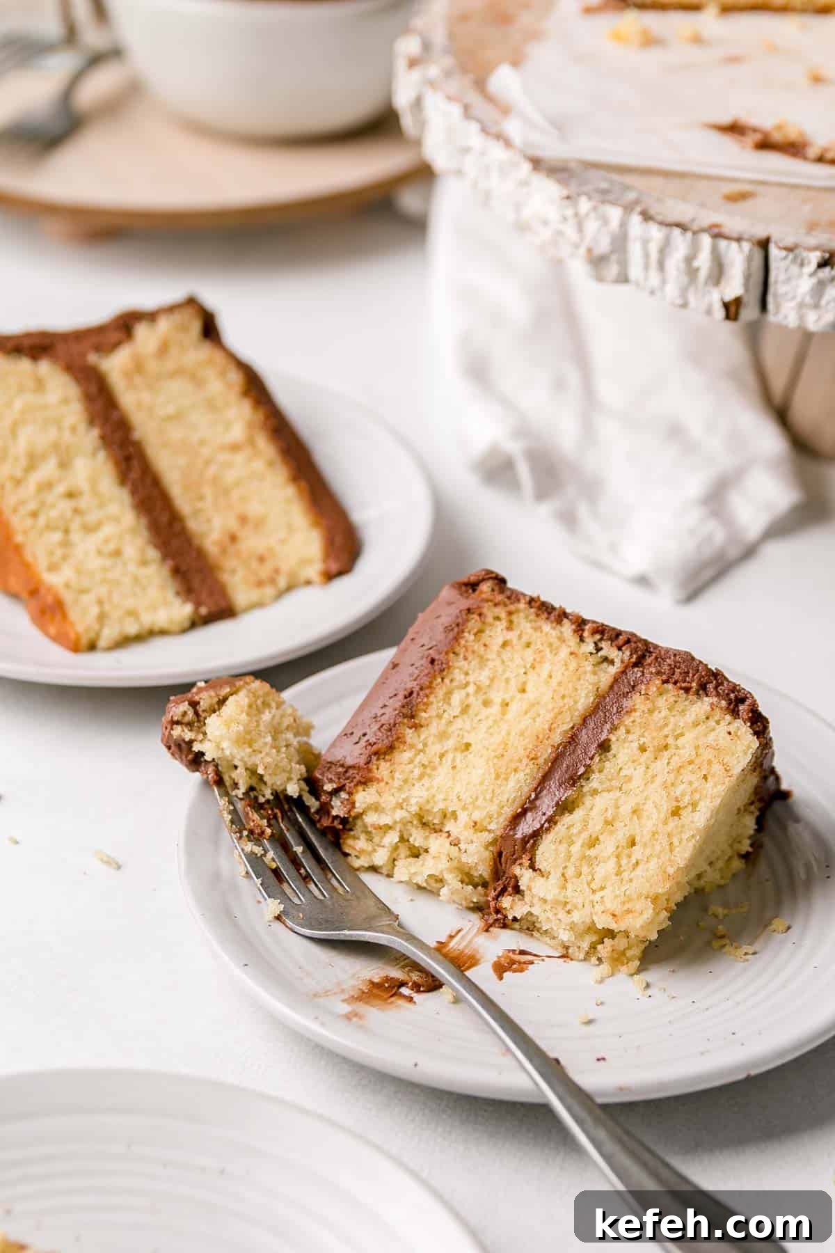 Gluten-free yellow vanilla cake slices on small plates, with bite on fork resting next to the slice.