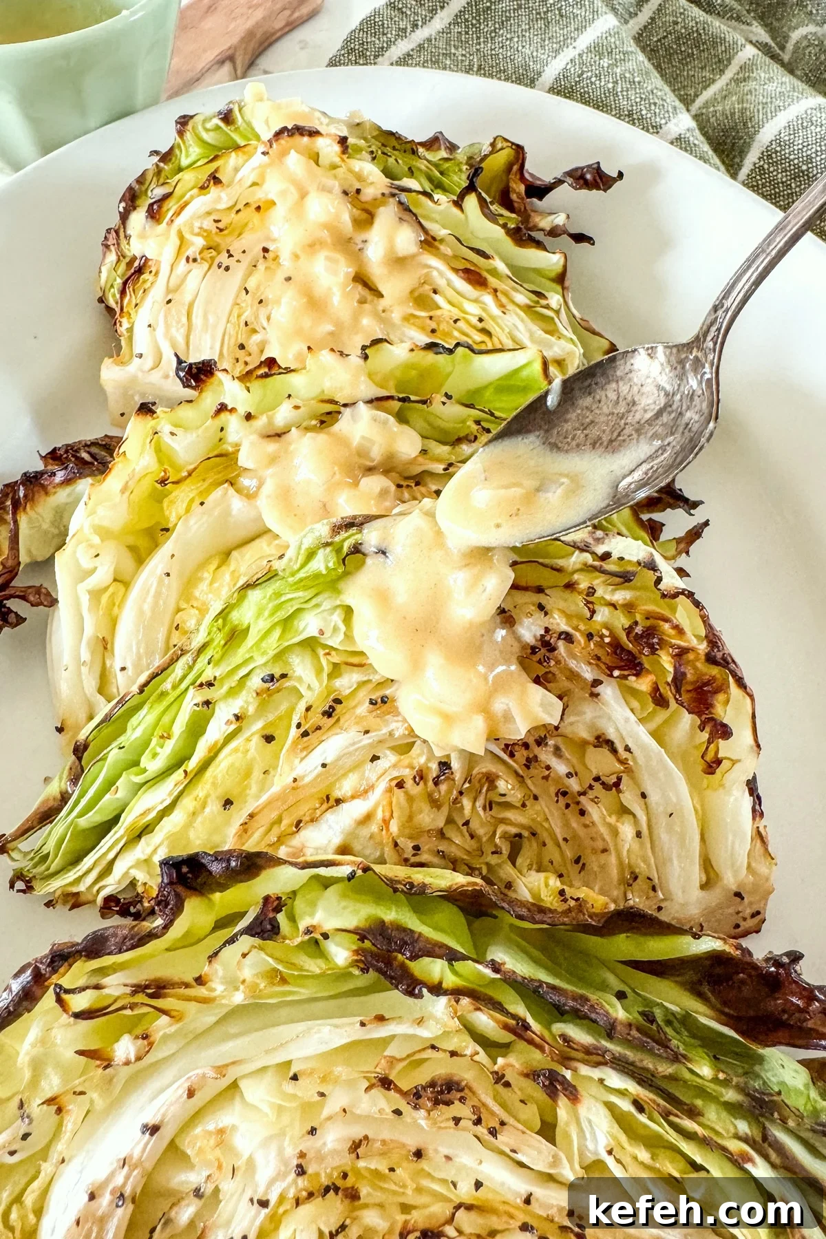 spooning sauce over roasted cabbage on platter