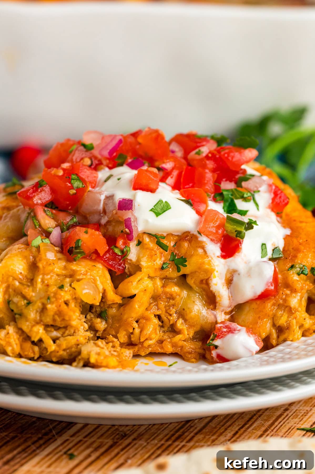 A plate of chicken enchiladas topped with sour cream and tomatoes