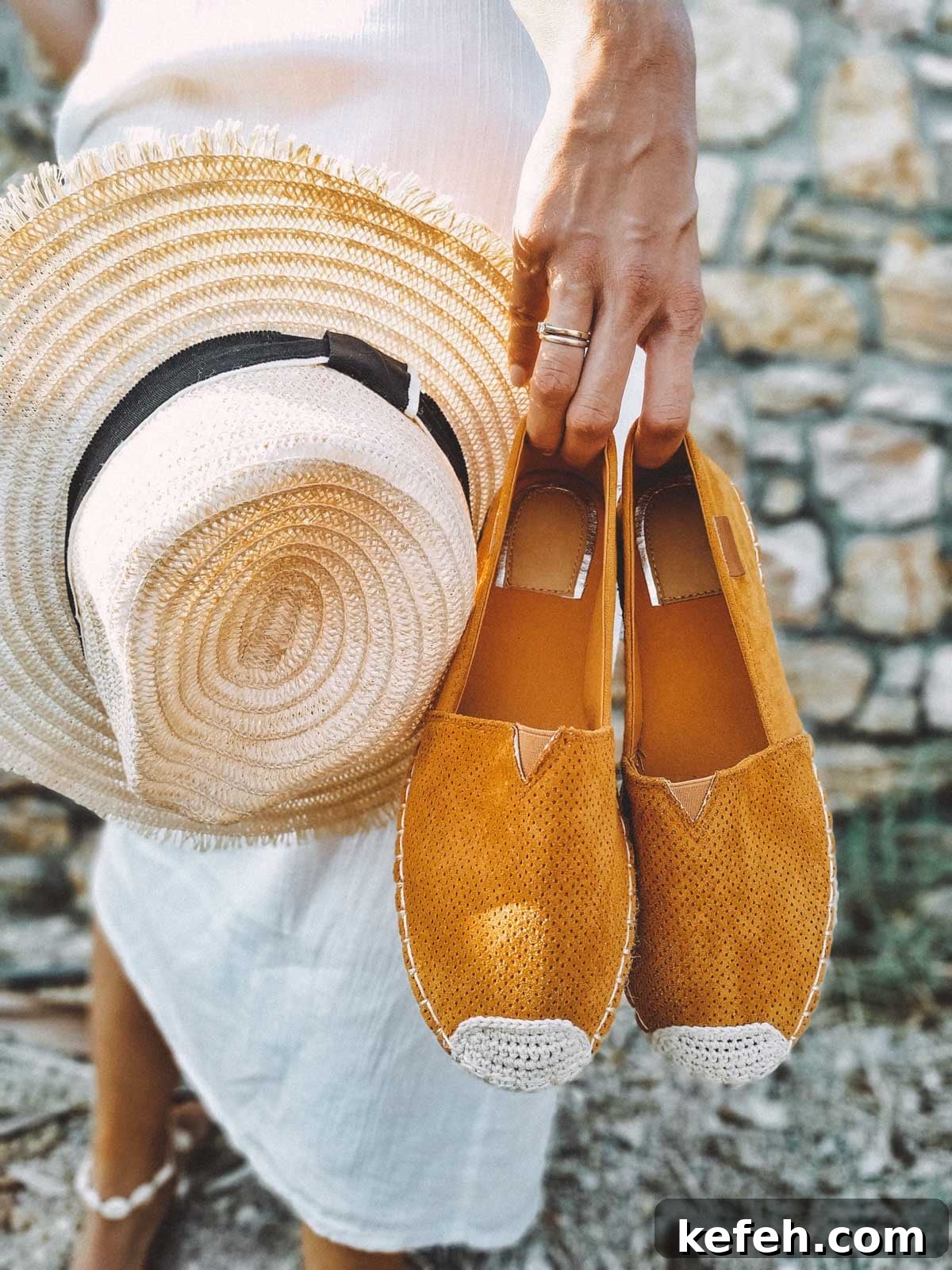 How I Built a Streamlined Summer Capsule Wardrobe 2 Woman in a white linen dress from a summer capsule wardrobe holding mustard yellow espadrilles and a straw sun hat