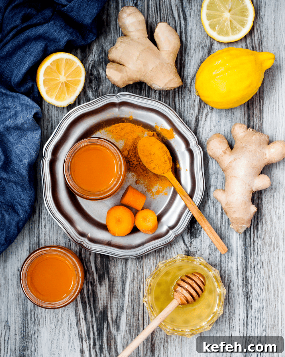 Anti-Inflammatory ingredients like ginger, lemon, turmeric, lemons and carrots on a gray wooden table
