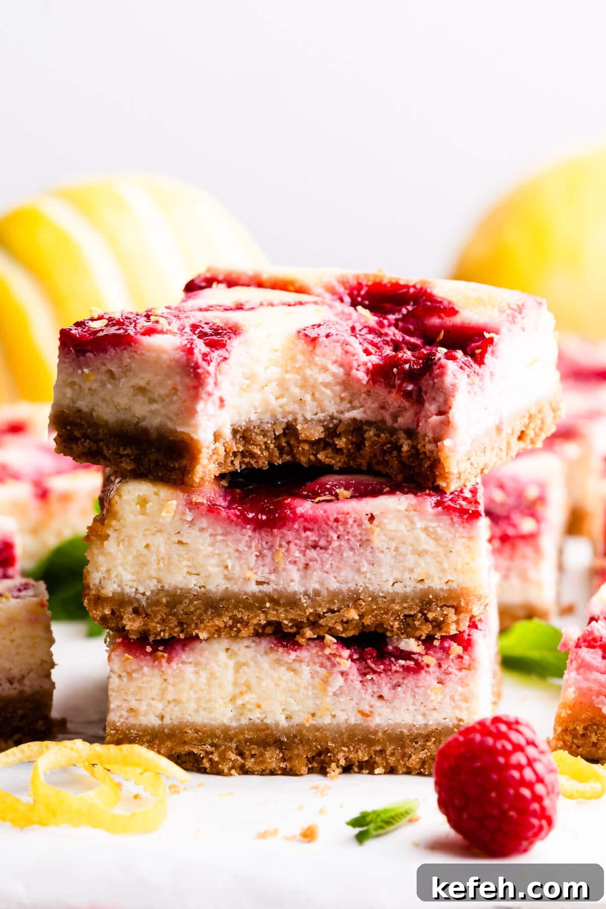 side super close up of a stack of three cheesecake bars with the top one missing a bite