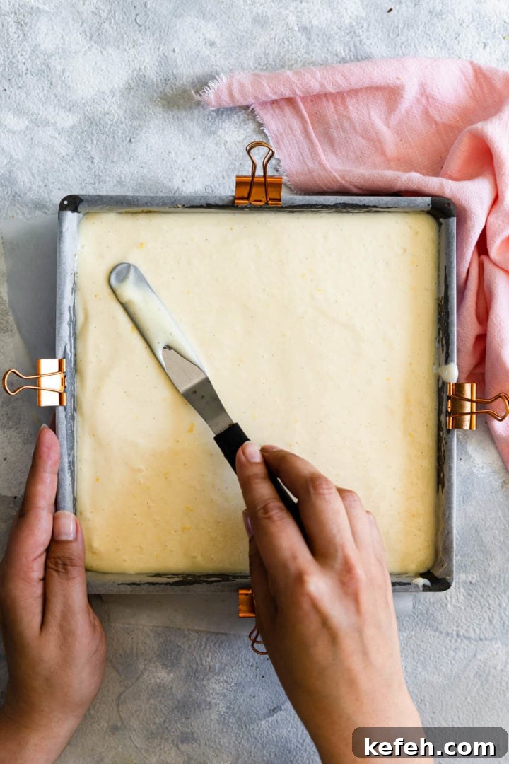 top view of a person smoothing the batter in a baking tin