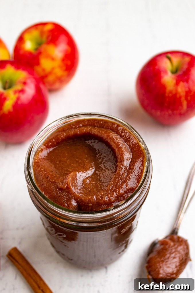 Moist Apple Butter Muffins with Warm Cinnamon Flavor 3 A jar of apple butter with apples in the background.