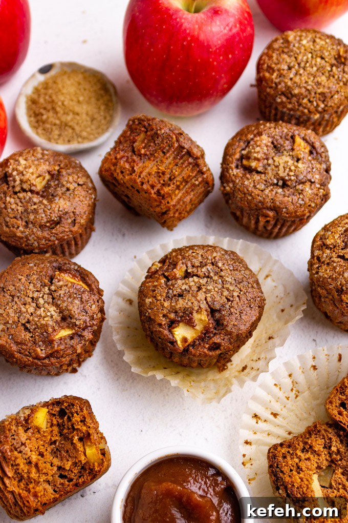 Moist Apple Butter Muffins with Warm Cinnamon Flavor 6 Angled shot of apple butter muffins with paper muffin wrappers and apples
