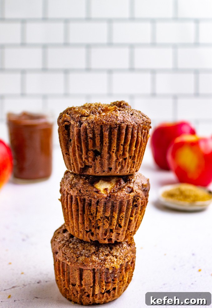 Moist Apple Butter Muffins with Warm Cinnamon Flavor 7 a stack of healthy apple butter muffins with apples in the background.