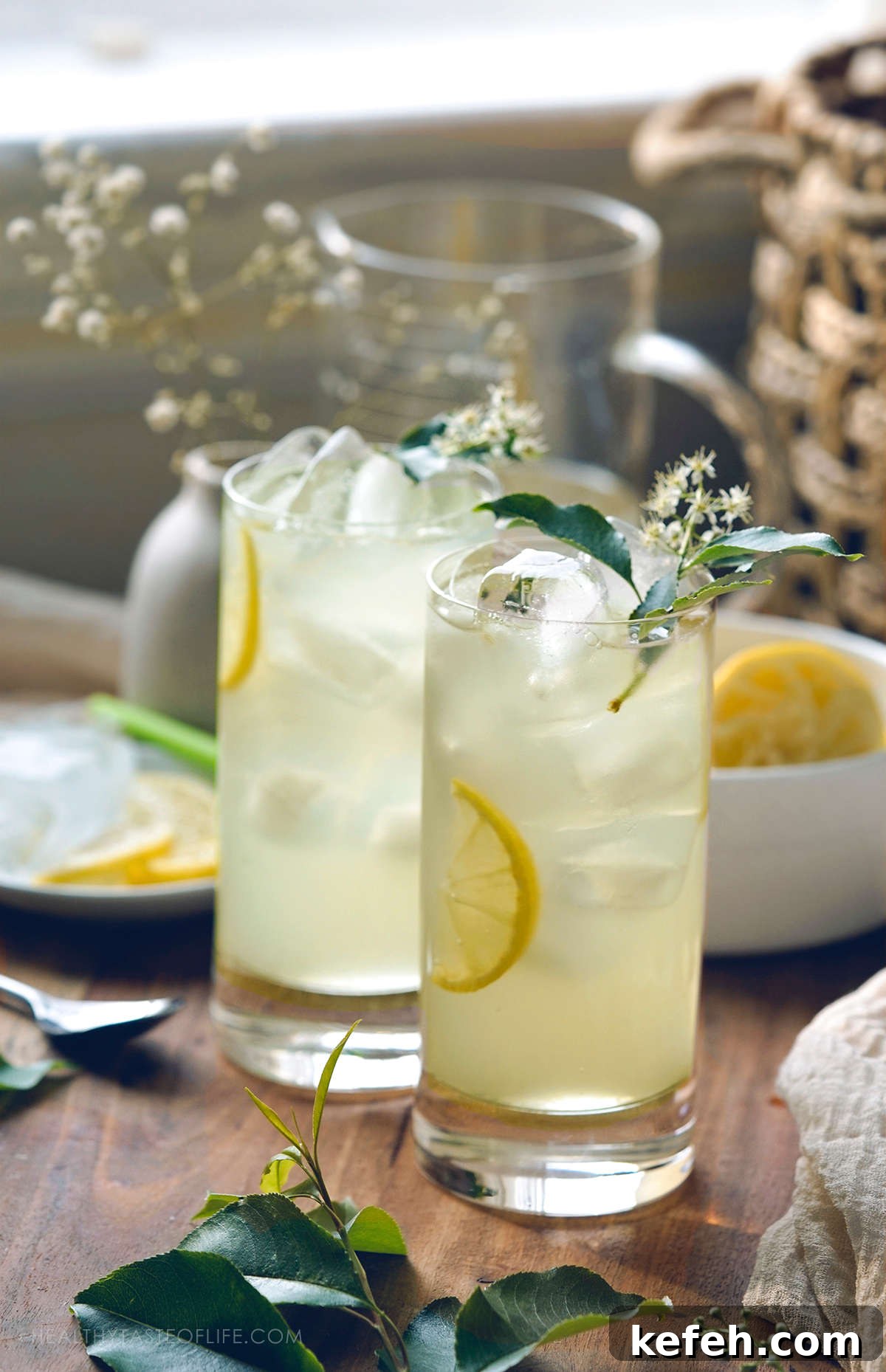 Close up shot of iced elderflower lemonade with cordial and garnished with lemon and elderflower leaves.