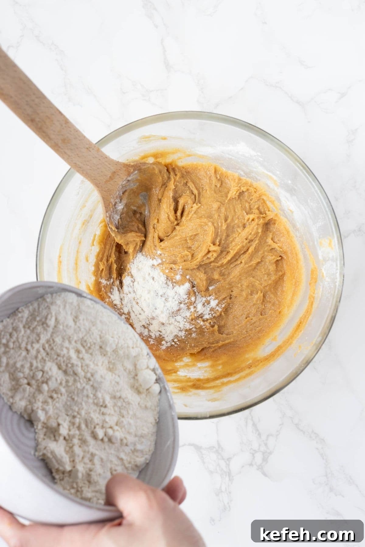 Flour being added to peanut butter cookie dough while making sourdough discard peanut butter cookies.