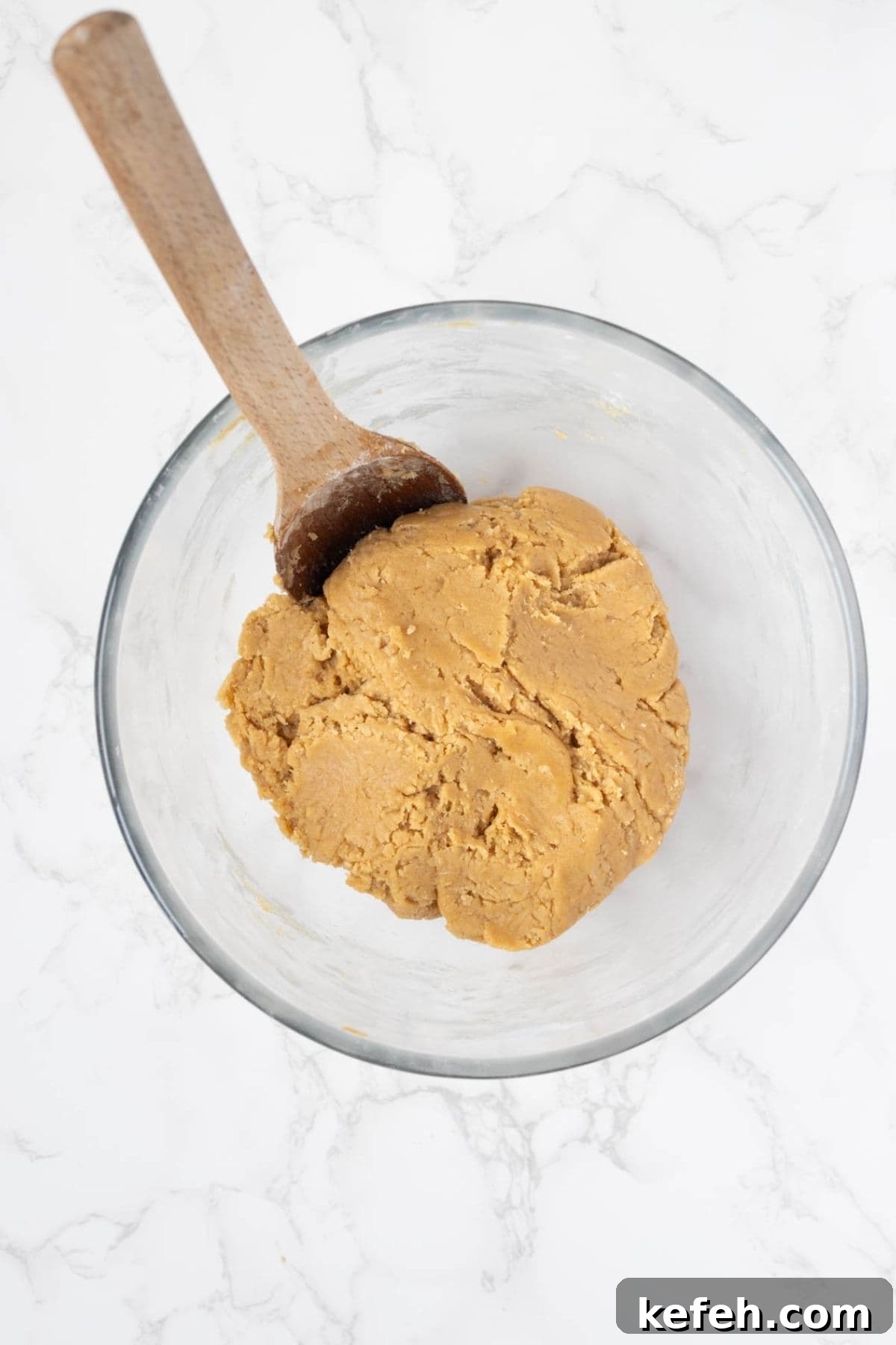 Finished sourdough peanut butter cookie dough in a glass mixing bowl ready for shaping.