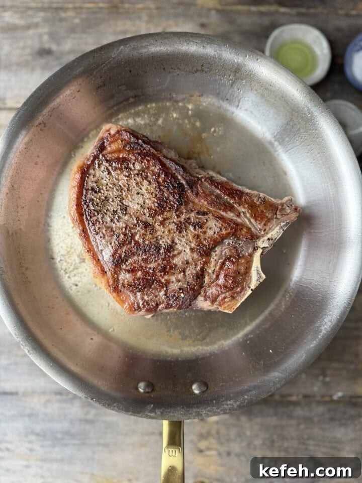 T-Bone Steak Recipe with Garlic Butter and Herbs 11 flipped T-bone in a stainless steel pan with oil
