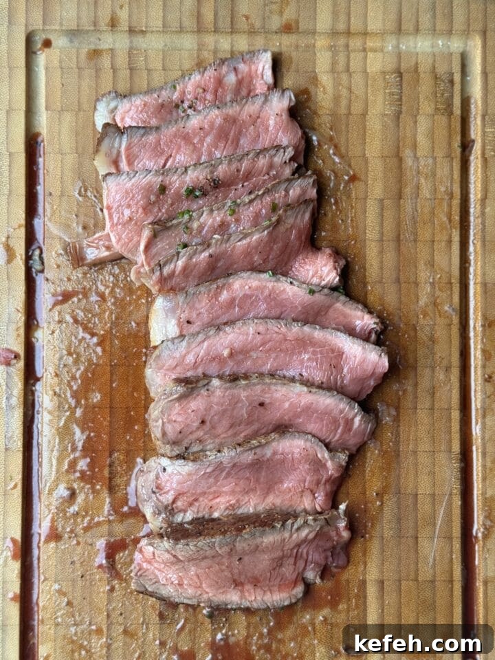 T-Bone Steak Recipe with Garlic Butter and Herbs 13 Seared steak sliced on a wooden cutting board, seasoned and cooked to perfection.