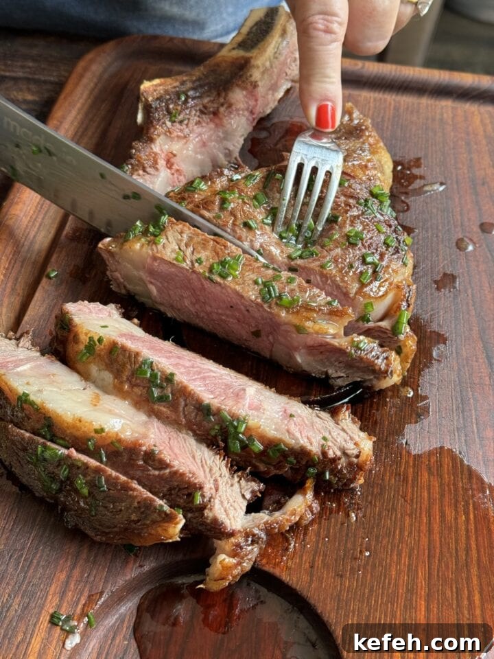 T-Bone Steak Recipe with Garlic Butter and Herbs 7 Juicy, cooked steak cut on a wooden board with fresh herbs, showcasing a perfect medium-rare center.
