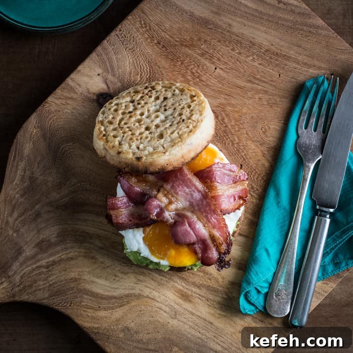 Breakfast Crumpet Burger on a wooden board with a knife and fork and a cup of coffee