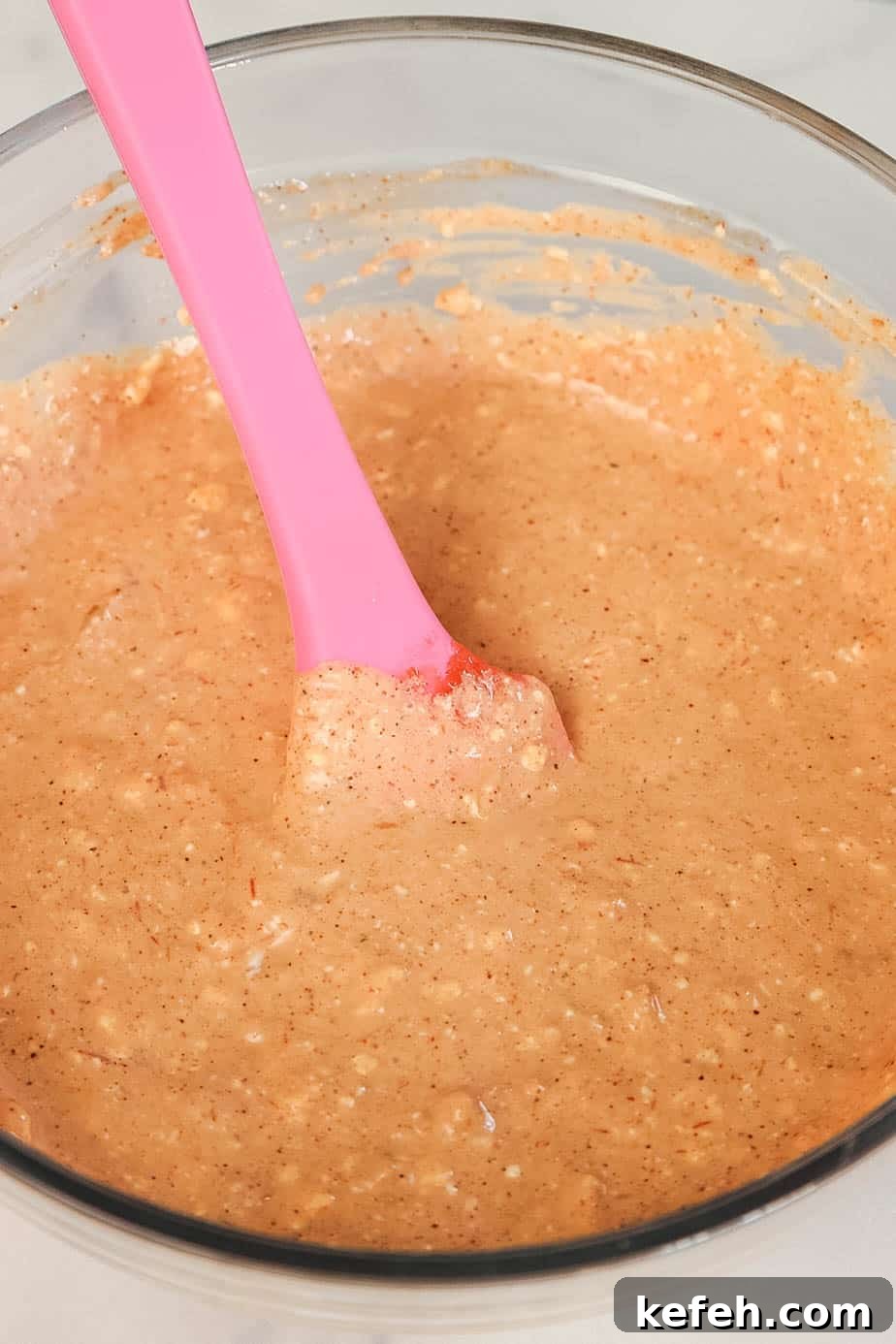 Cream Cheese Salsa Dip Recipe for Parties and Game Day 4 A glass bowl of cream cheese, salsa, and taco seasoning mixture being stirred with a spatula.
