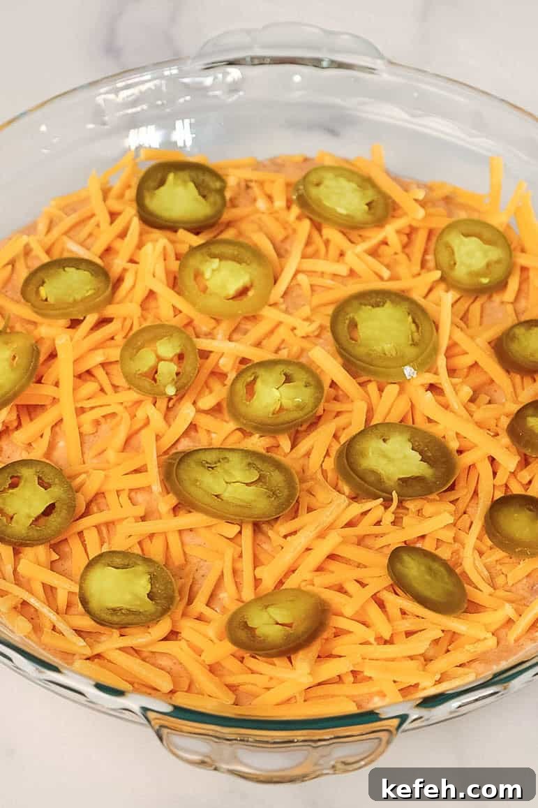 Cream Cheese Salsa Dip Recipe for Parties and Game Day 6 A close-up of the assembled dip with shredded cheddar cheese and jalapeño slices layered over the creamy base.