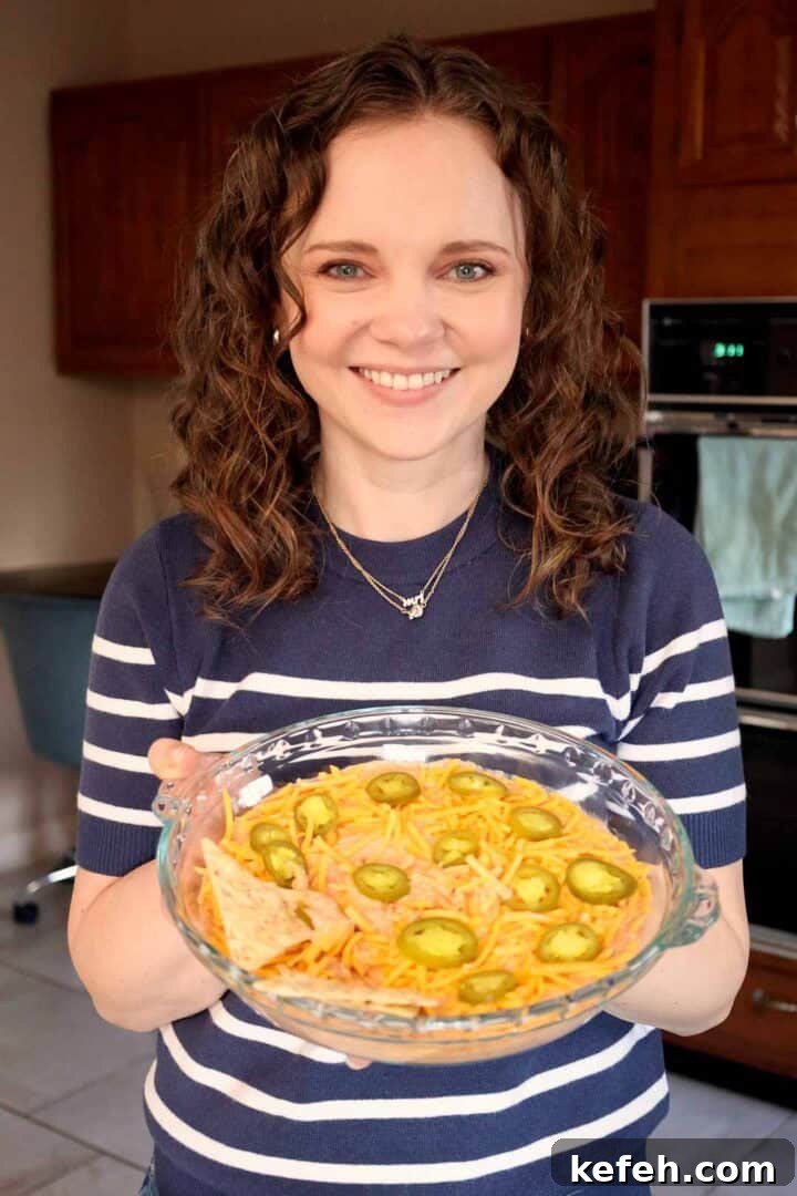 Cream Cheese Salsa Dip Recipe for Parties and Game Day 9 Kelsey Smith holding a glass pie dish of creamy salsa dip.