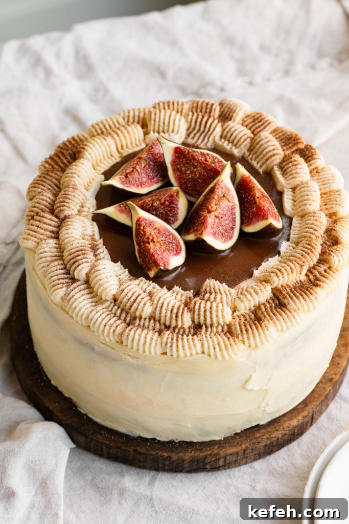 Warm Caramel Apple Spice Cake Recipe 2 Frosted apple spice cake topped with caramel and sliced figs in a round wooden serving board.