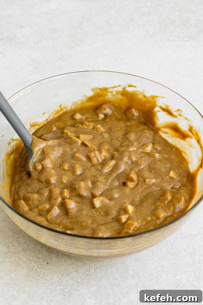 Warm Caramel Apple Spice Cake Recipe 7 Apple cake batter in a large bowl with a spatula.