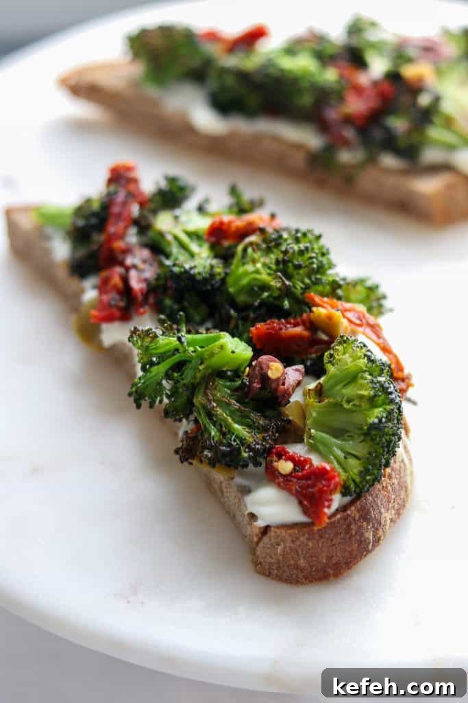 A close up of an open sandwich with ricotta, broccoli and sun-dried tomatoes