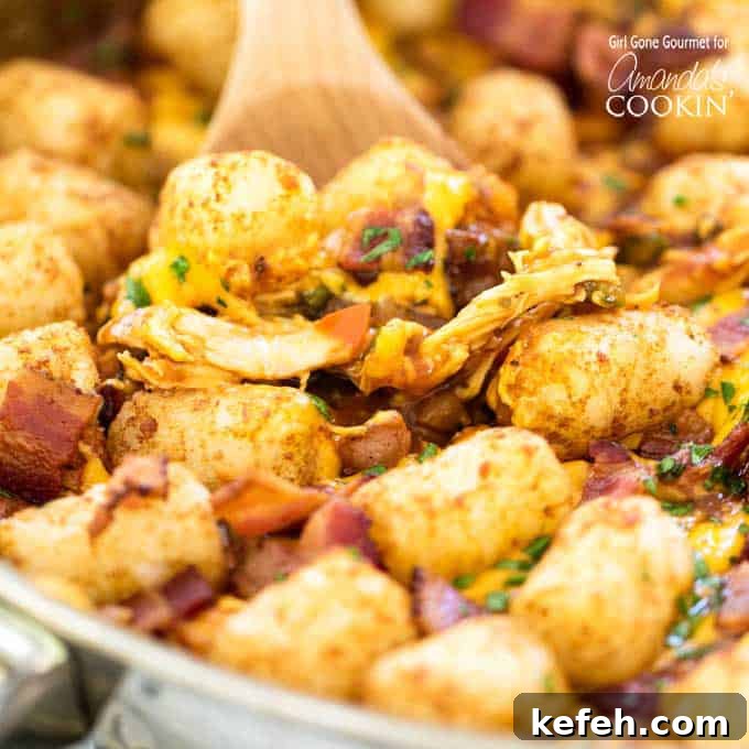 BBQ chicken, tater tots, and bacon in a skillet with wooden spoon