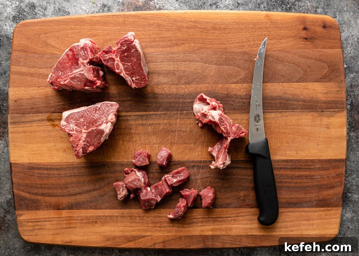overhead: slicing lamb into bite size pieces on cutting board with knife