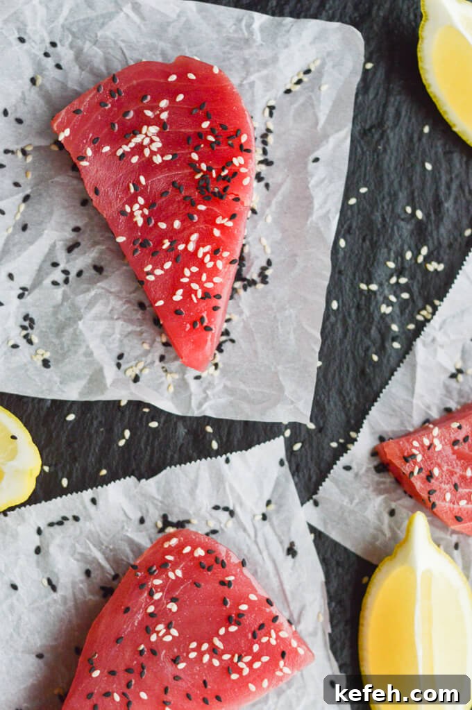 Spicy Peanut Ahi Tuna Salad with Sesame Ginger Dressing 3 3 uncooked ahi tuna steaks with black and white sesame seeds on parchment paper with wedges of lemons scattered around.