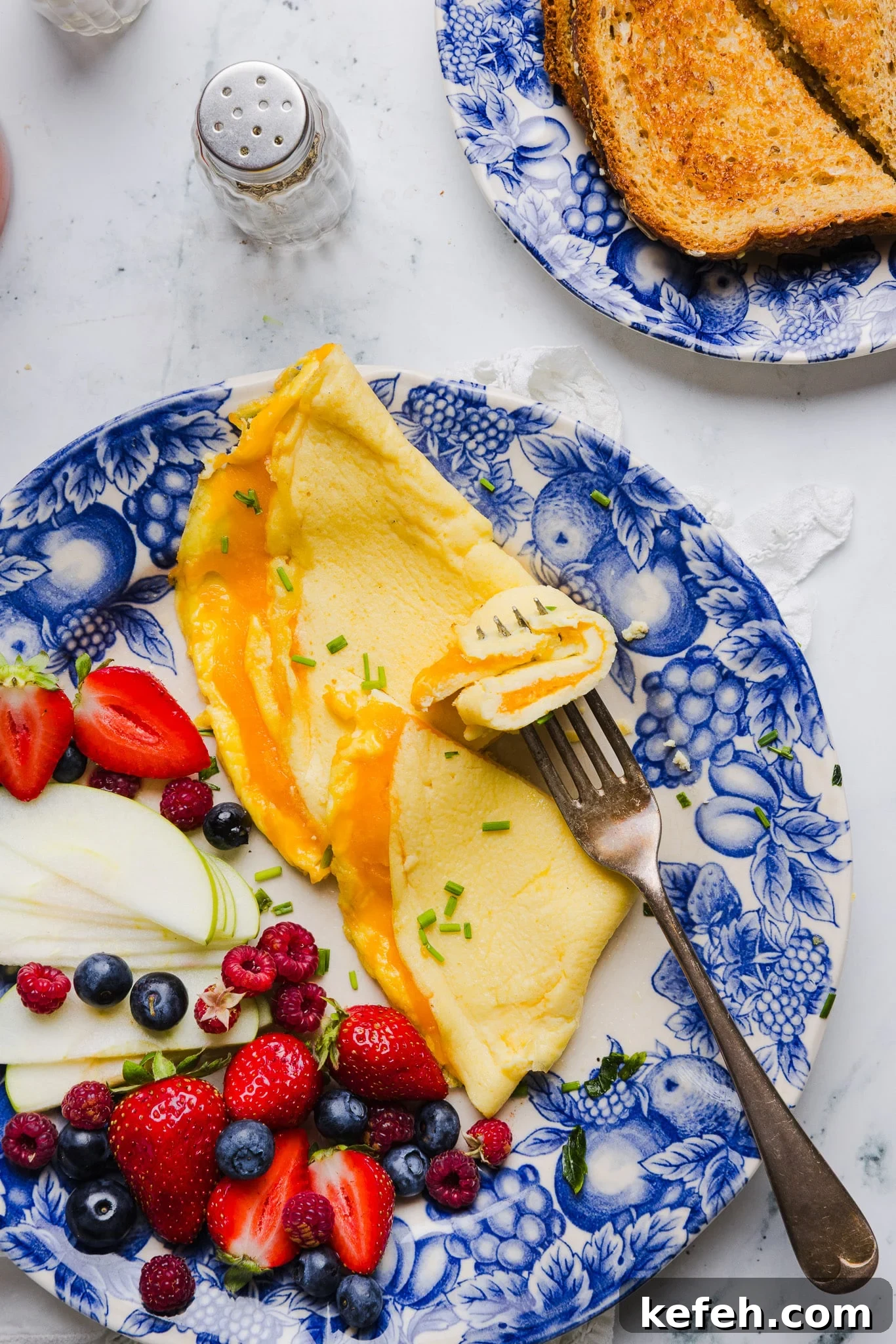 This easy cottage cheese omelette is loaded with creamy, salty cottage cheese and sharp cheddar. It's a protein powerhouse! A fork taking a bite from a cottage cheese omelette.