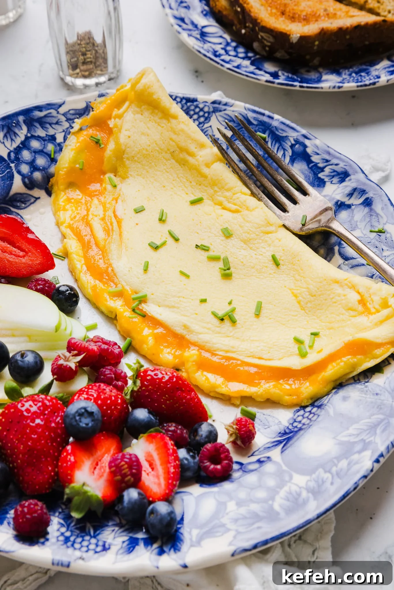 This easy cottage cheese omelette is loaded with creamy, salty cottage cheese and sharp cheddar. It's a protein powerhouse! A cottage cheese omelette on a plate with fresh fruit.